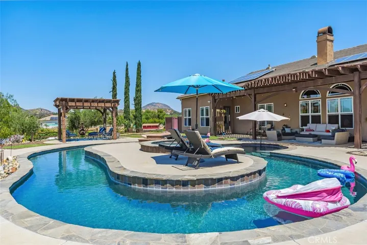 Resort style pool with baja step, inviting lazy river, spa with waterfall, bridge to center island & expansive lounging deck