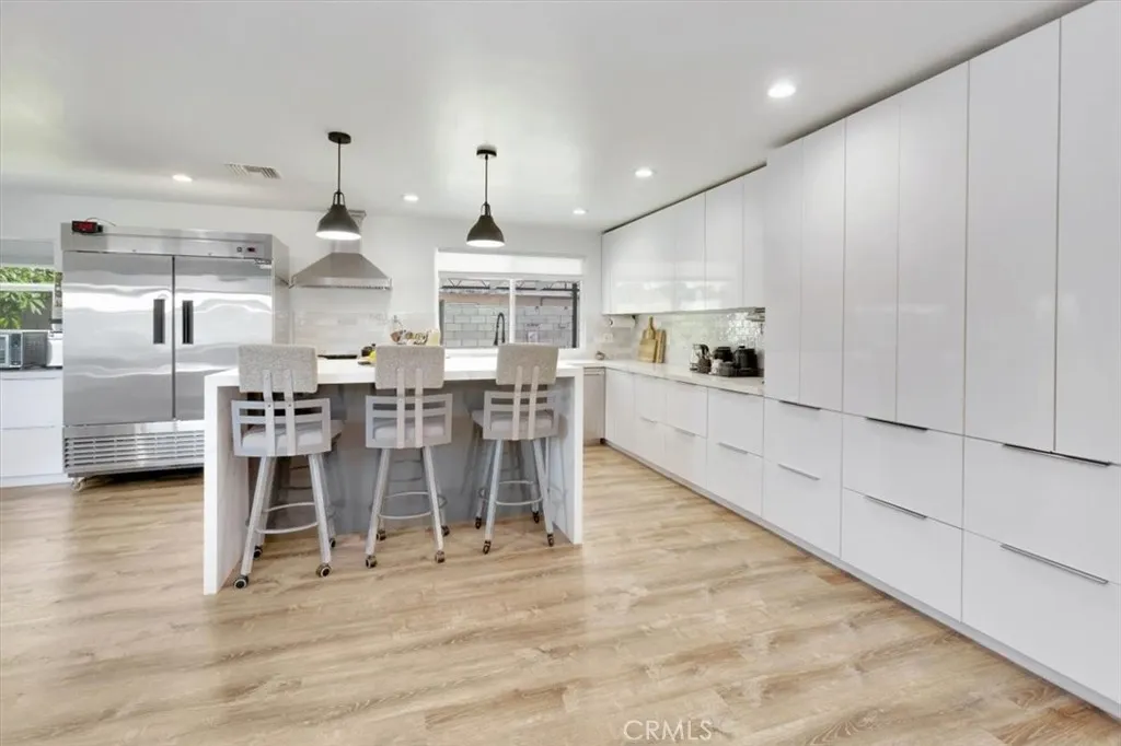 A chef's kitchen with plenty of space for storage. Gas range and oven to left of sink, dishwasher to right of sink. (Pictured is restaurant double refrigerator and is EXCLUDED from sale.)