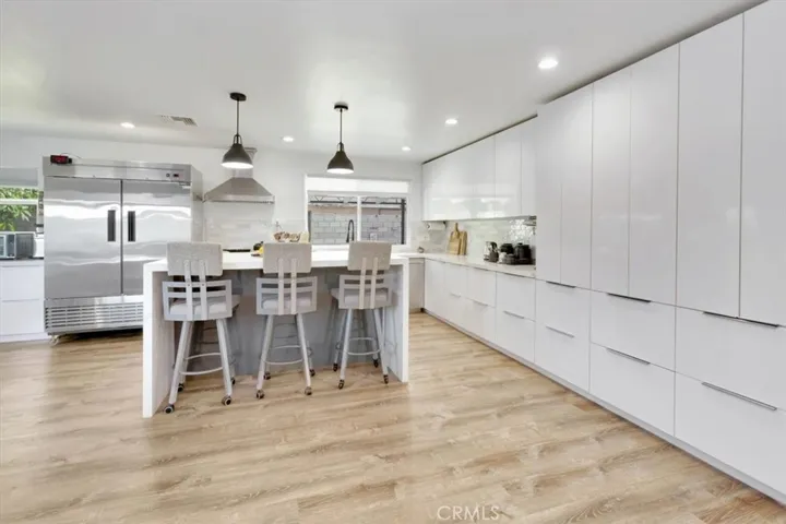 A chef's kitchen with plenty of space for storage. Gas range and oven to left of sink, dishwasher to right of sink. (Pictured is restaurant double refrigerator and is EXCLUDED from sale.)