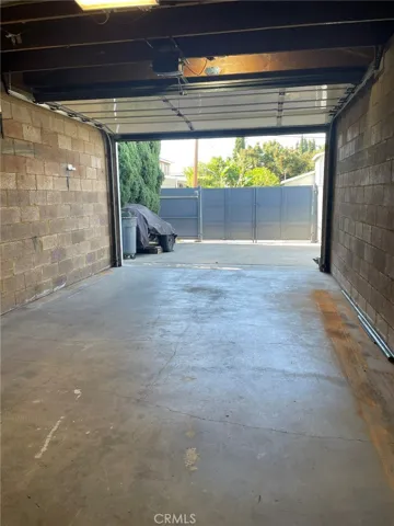 View from interior towards opened garage door and special Australian gating for secure driveway and utilitarian area.