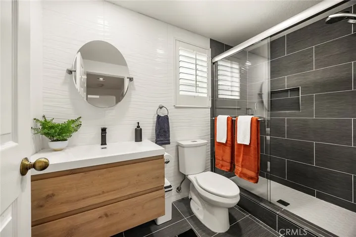 Completely remodeled ground level bathroom is adjacent to ground level bedroom, convenient for guests or those who don't do stairs. Note the spacious walk-in shower. Glass enclosure helps to make this bath feel more open.