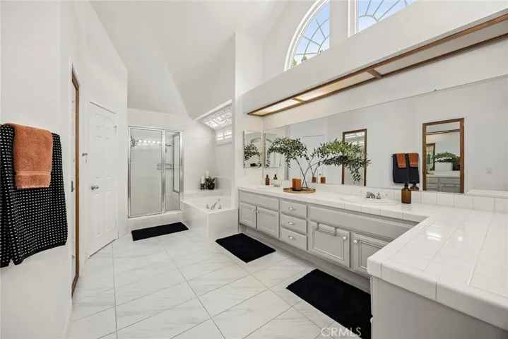 Spacious en suite primary bath is designed for a daily spa experience. It includes a separate soaking tub, a walk-in shower with glass enclosure, dual sink vanity and 2 walk-in closets. There is also a private commode and vanity make-up station.