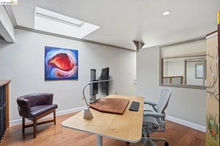 Dedicated workspace featuring a skylight and wood-finish flooring