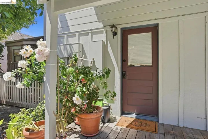 Rear entry featuring a paneled door with a privacy window, exterior wall sconce, and a wood-plank porch