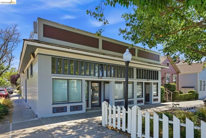 Commercial-style facade with large display windows, a prominent entrance, and a white picket fence