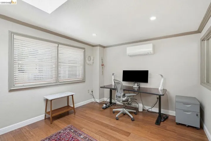 Bright interior space featuring wood-finish flooring, a wall-mounted mini-split system, recessed lighting, and a skylight