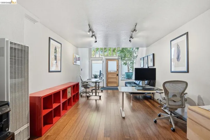 Wood-finish flooring throughout, track lighting, and a front entry door with transom window