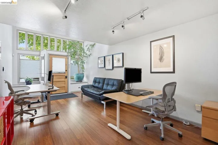 High ceilings featuring track lighting, wood-finish flooring, a wood entry door with frosted glass, and transom windows