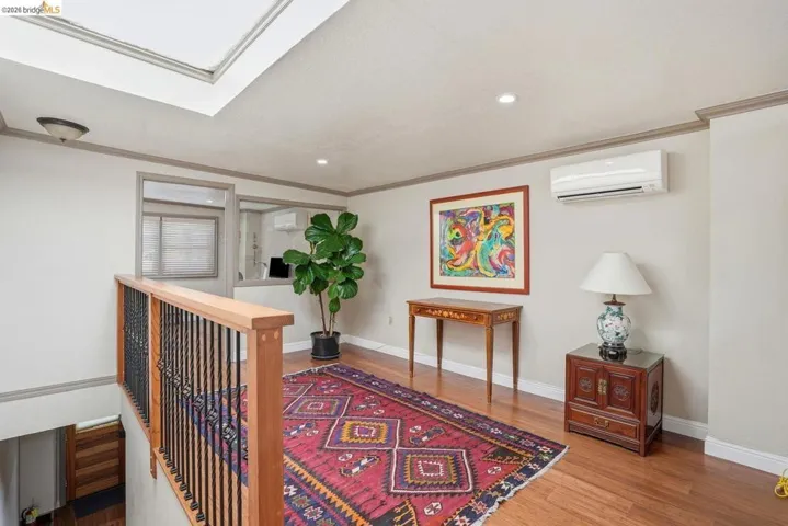 Upper-level landing featuring wood-finish flooring, a skylight, recessed lighting, and a wall-mounted climate control unit
