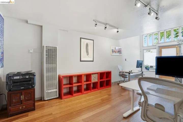 Bright interior space featuring wood-finish flooring, white walls, and track lighting
