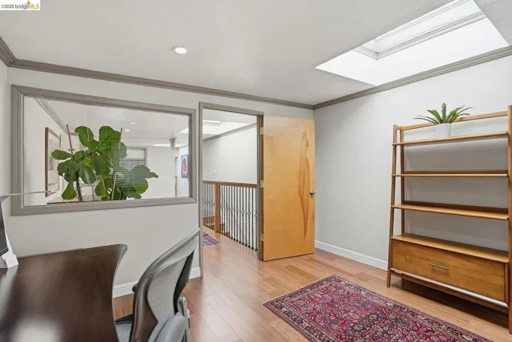 Hardwood-finish flooring throughout, featuring a skylight, recessed lighting, and a glass interior wall