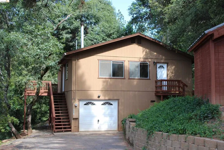 Brown siding exterior with a white garage door featuring decorative windows