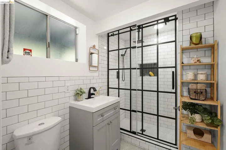 Modern bathroom featuring a contemporary vanity with a white countertop and matte black faucet, a glass-enclosed shower with black grid detailing, white subway tile walls, and hexagonal mosaic floor tiling