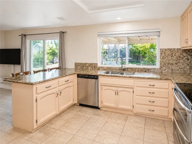 Kitchen with granite counters, breakfast bar, and backyard views.