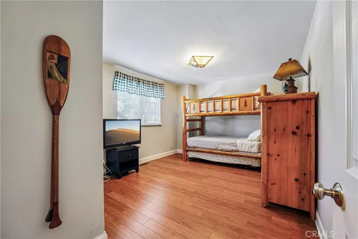Additional bedroom with wood-style flooring, bunk-style sleeping setup, natural light, and flexible use for guests, recreation, or mountain getaway living.