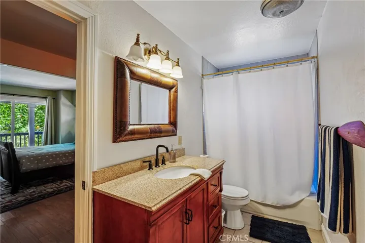 Bathroom with granite vanity, updated fixtures, warm cabinetry, tub-shower combination, and convenient access from the nearby bedroom area.