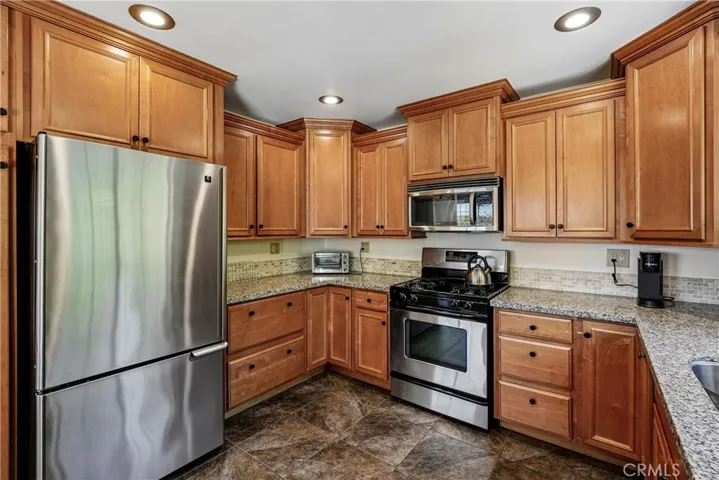 Kitchen with generous cabinet storage, granite counter space, stainless refrigerator and range, and a functional layout connected to the main living areas.