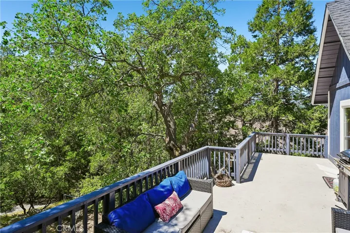 Spacious upper deck surrounded by trees with far mountain and treetop views, creating an inviting outdoor living area for relaxing, dining, and enjoying the Lake Arrowhead lifestyle.