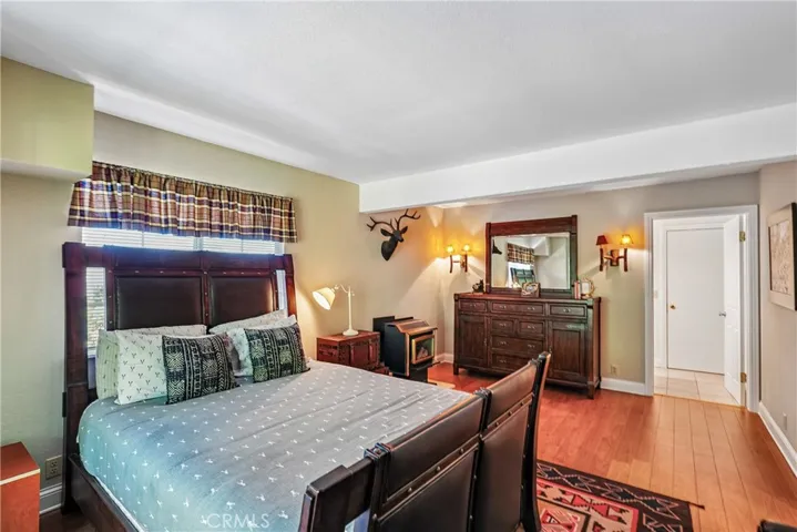 Private bedroom retreat with warm wood-style flooring, mountain-inspired decor, generous wall space, and a comfortable layout near the adjoining bath area.