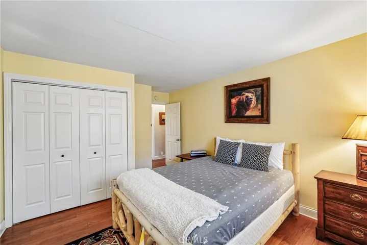 Guest bedroom with closet storage, wood-style flooring, warm wall tones, and a functional layout for full-time living, guests, or weekend stays.