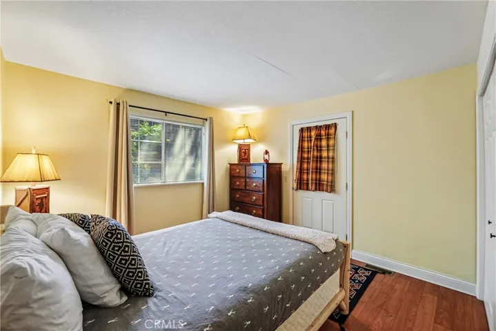 Comfortable guest bedroom with wood-style flooring, generous window light, closet storage, and a warm mountain-home atmosphere.