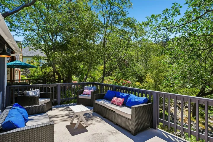 Outdoor deck seating area surrounded by trees, offering a peaceful place to relax, entertain, and enjoy the Lake Arrowhead mountain setting.