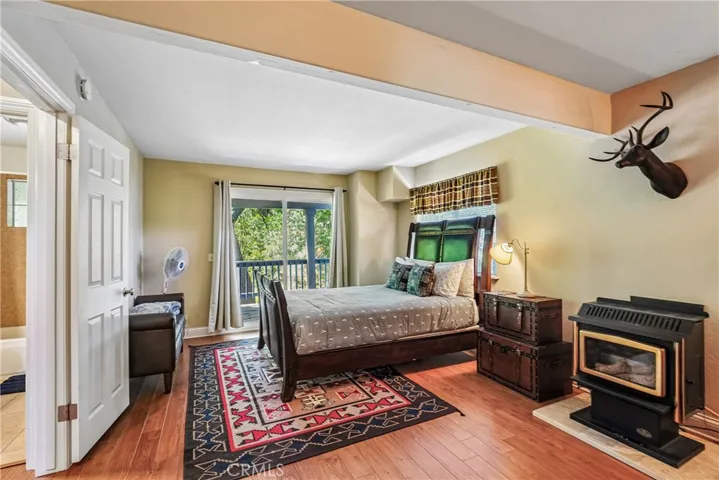 Comfortable private retreat with wood-style flooring, deck access, warm mountain-inspired details, and a cozy freestanding stove that adds character and four-season appeal.