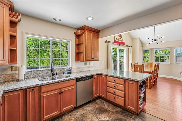 Bright kitchen with granite counters, warm wood cabinetry, stainless appliances, treetop window views, and an open connection to the dining and living spaces for everyday mountain living.