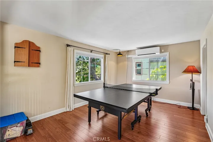 Spacious flex room with wood-style flooring, treetop windows, and versatile potential for a game room, lounge, office, or guest overflow space.