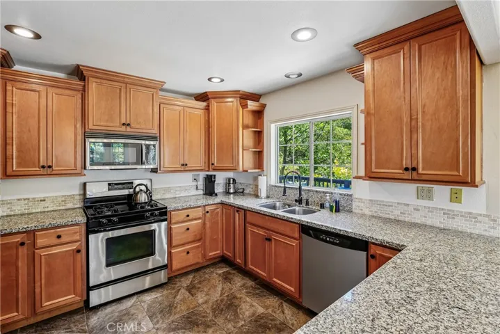 Updated kitchen with granite counters, stainless appliances, warm cabinetry, recessed lighting, and efficient workspace for everyday use or weekend mountain stays.