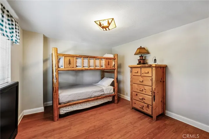 Additional bedroom with warm wood-style flooring, mountain-style furnishings, closet storage, and flexible space for guests or everyday living.