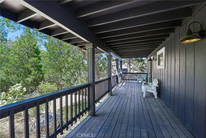Covered lower deck and walkway area offering shaded outdoor space, mountain-style railing, and access around the home’s exterior.