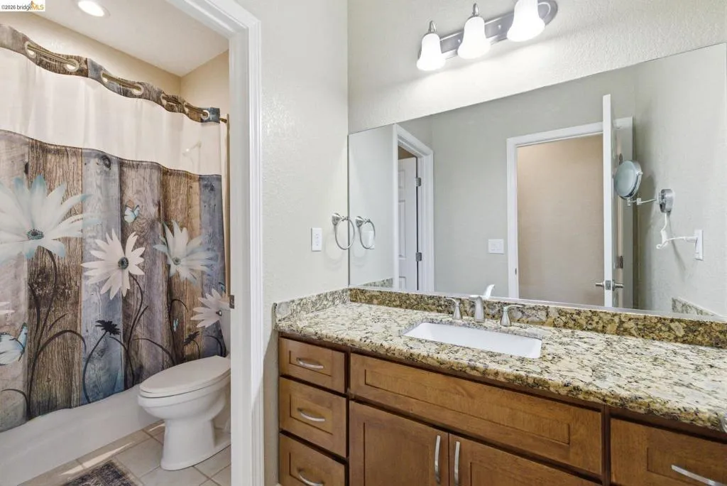 Full bathroom featuring vanity, a shower with curtain, light tile patterned floors, and a textured wall
