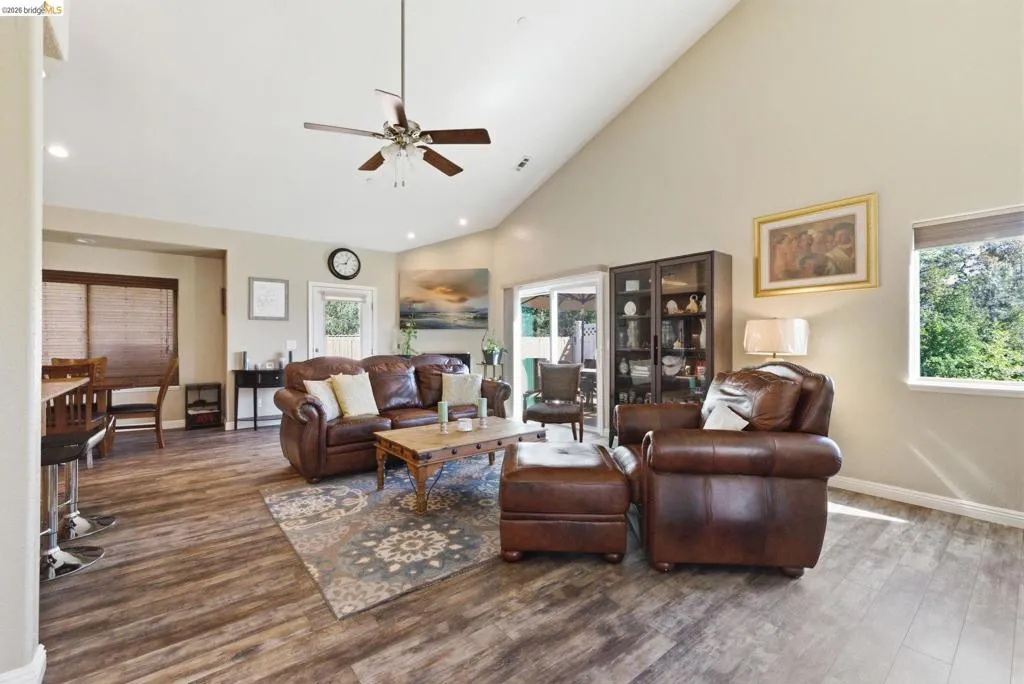 Living area featuring ceiling fan, wood finished floors, plenty of natural light, lofted ceiling, and recessed lighting