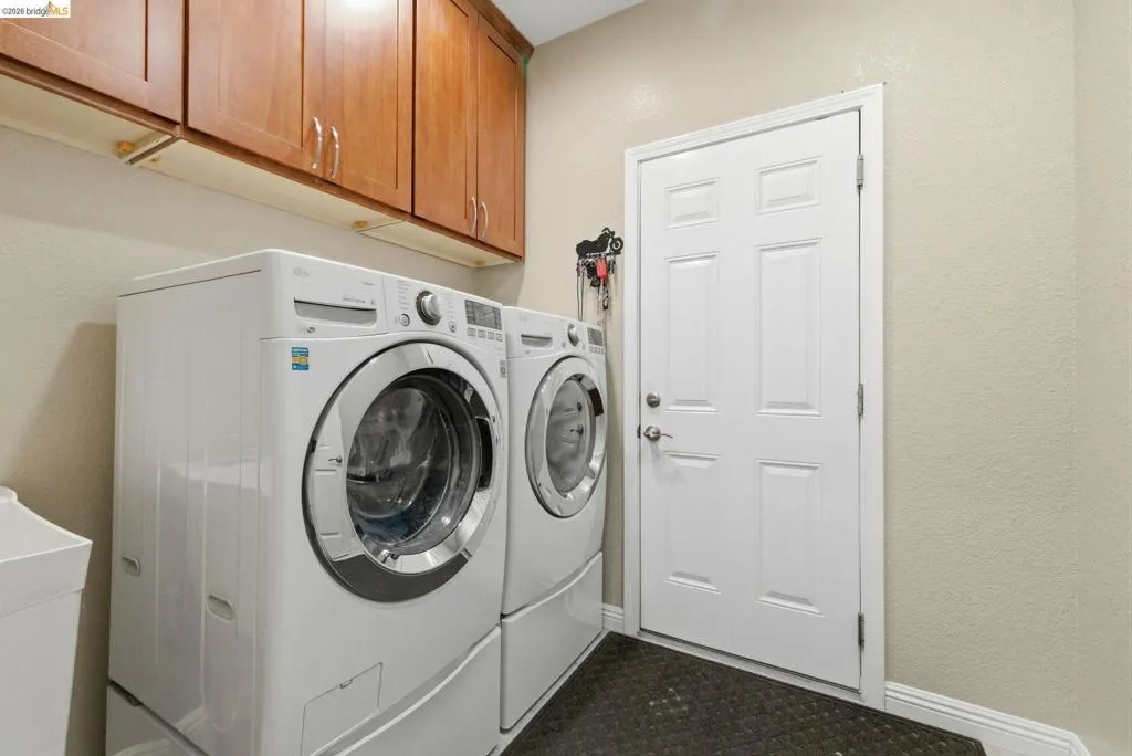 Laundry area featuring cabinet space, a textured wall, and separate washer and dryer