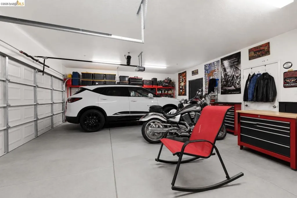 Spacious garage featuring a concrete floor, overhead lighting, and white panel garage doors