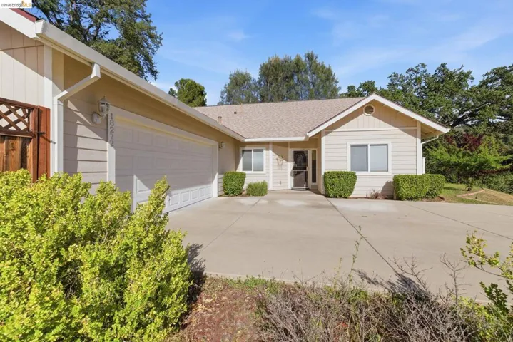 Ranch-style house featuring a garage, driveway, and roof with shingles