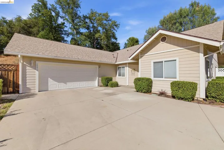 Ranch-style home featuring a shingled roof, an attached garage, and concrete driveway