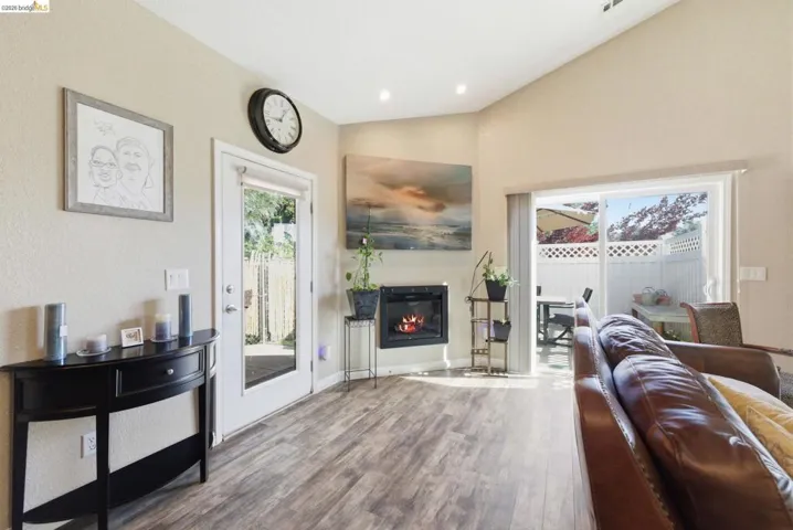 Living room featuring wood finished floors, lofted ceiling, a glass covered fireplace, and recessed lighting