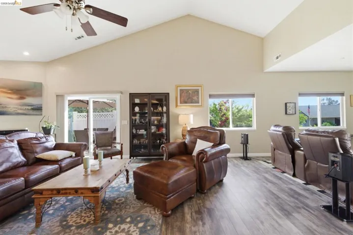 Living room with hardwood / wood-style floors, ceiling fan, healthy amount of natural light, and a high ceiling