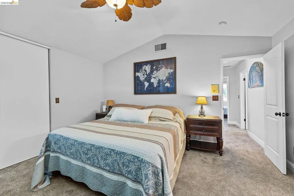 Carpeted room with a vaulted ceiling and a ceiling fan with light fixture