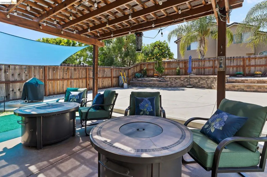 Patio featuring a wood pergola with string lights, concrete flooring, and a privacy fence
