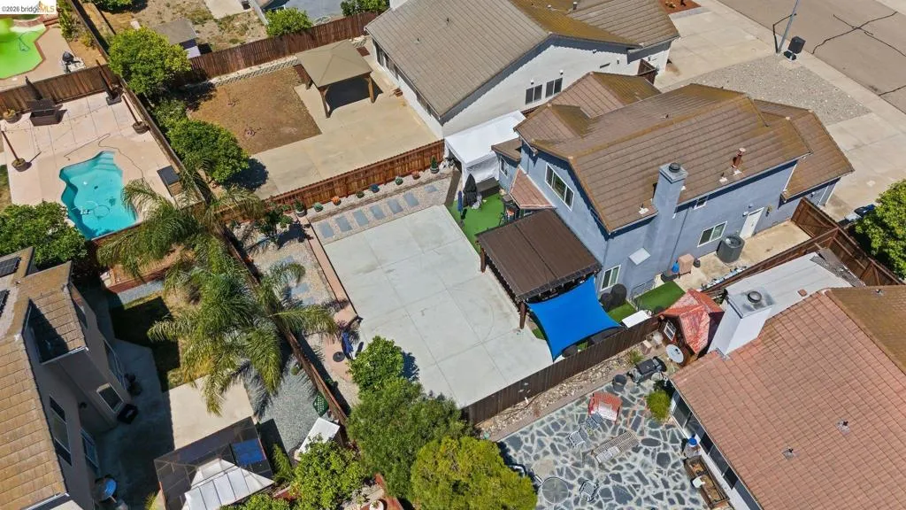 Aerial perspective showcasing a property with a concrete patio, a covered pergola, and a visible swimming pool