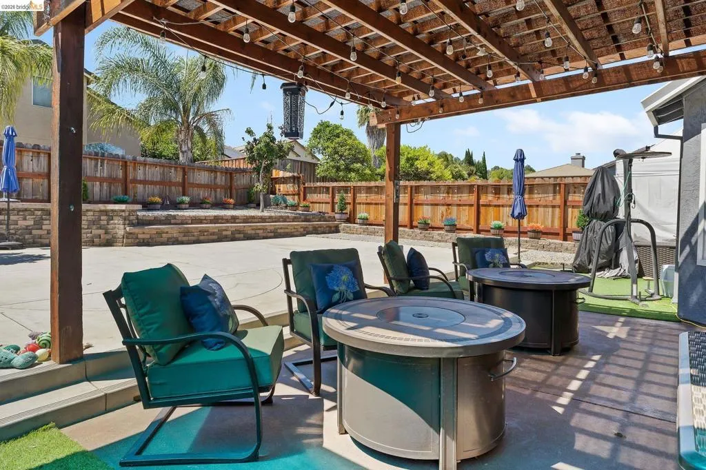 Expansive concrete patio with a wooden pergola featuring string lighting