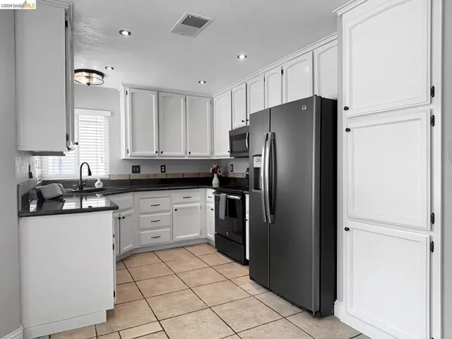 Kitchen featuring extensive white cabinetry, dark countertops, dark appliances, tile flooring, and recessed lighting