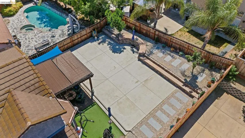 Expansive concrete patio area featuring a covered outdoor structure and a dedicated artificial turf section