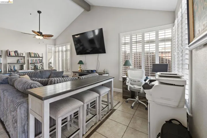 Living area featuring vaulted ceilings, a ceiling fan, and tile flooring
