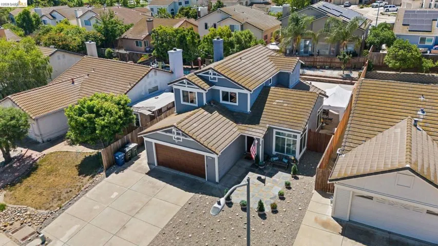Contemporary residence featuring a gray exterior, brown tile roof, and an attached garage with a wood-finish door