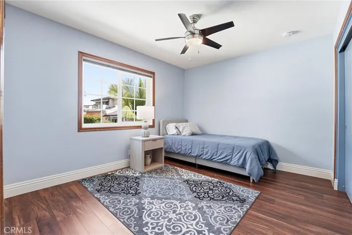 Bright secondary bedroom features wood flooring, soft natural light, and a comfortable layout. A welcoming space for family, guests, or a home office.