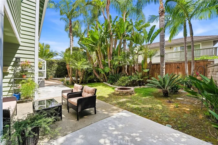 Tropical backyard oasis features mature palms, manicured greenery, and an inviting lawn area. The private setting offers plenty of room for gathering, entertaining, or simply unwinding outdoors.